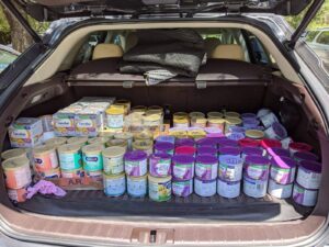 Car trunk filled with cans of baby formula ready for delivery.